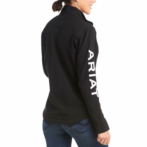 Person wearing a black jacket with ARIAT logo on sleeve