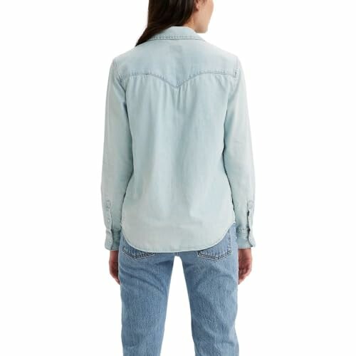 Back view of a person wearing a light denim shirt and jeans.