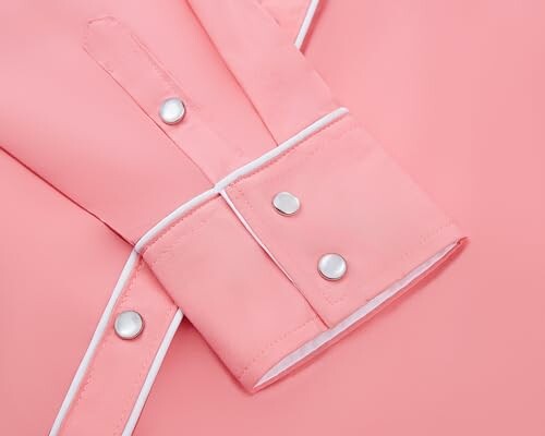 Close-up of a pink shirt cuff with white trim and silver buttons.