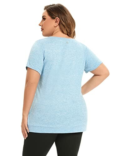 Back view of a plus-size woman wearing a light blue t-shirt and black pants.