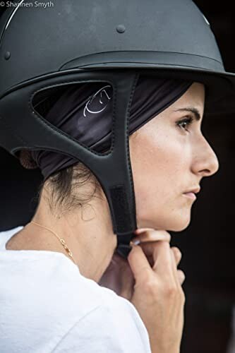 Woman adjusting black helmet.