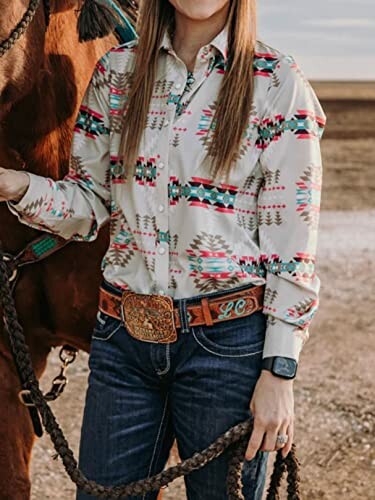 Woman in a patterned western shirt standing next to a horse.